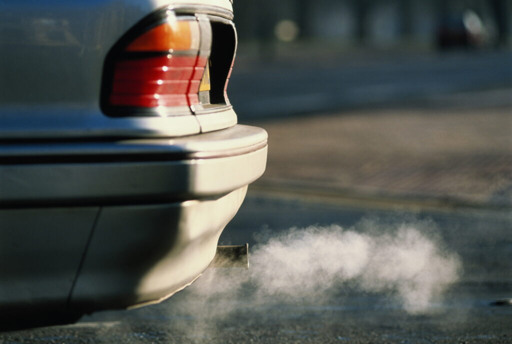 A car emits harmful smoke that pollutes and warms the air.