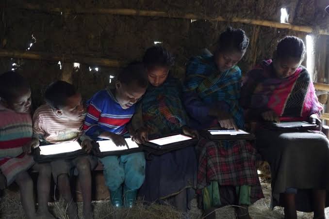 Children studying from tablets in a hut